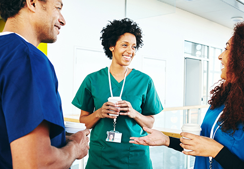 Three healthcare workers conversing in a hallway