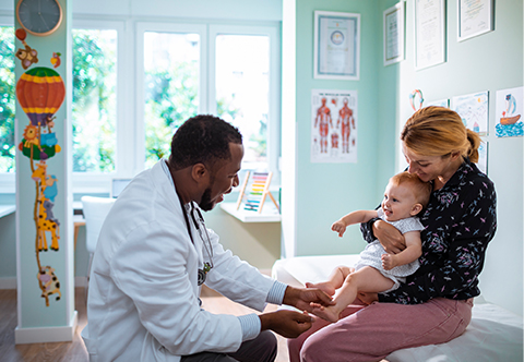 A physician examines a baby held by its mother